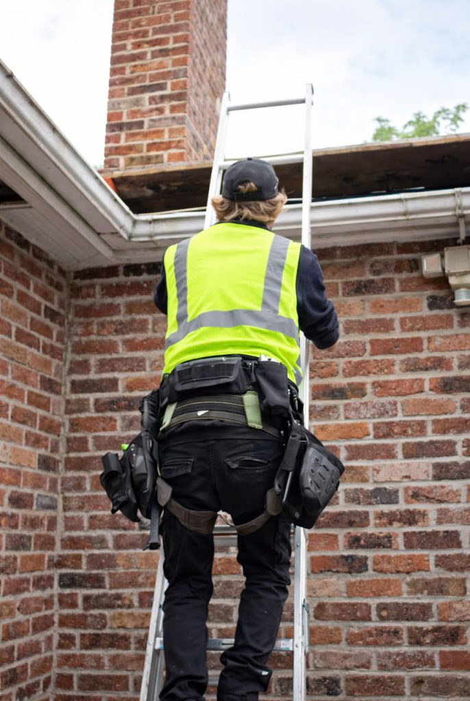 roofer on ladder repairing gutter